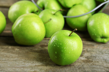 Ripe green apple in metal bucket on wooden table close up