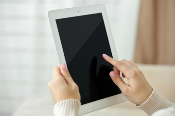 Female hand holding PC tablet on home interior background