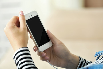 Music smartphone in female hand, on light background
