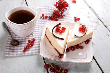 Tasty cheesecake with berries and cup of tea on table close up