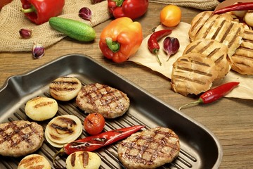 Fototapeta na wymiar Homemade pan-fried burgers in grill-pan on rustic dinning table.