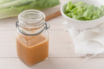 salad dressing in a glass container on light wooden background