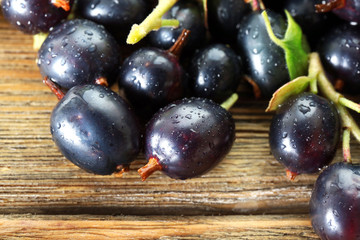 Pile of wet black currants on wooden table, closeup