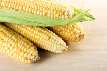 Fresh corn on cobs on wooden table, closeup