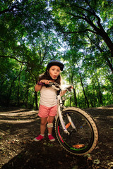 Plakat little girl with bicycle in summer park outdoors