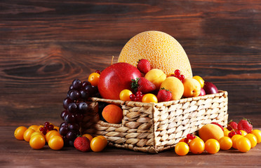 Assorted of fresh fruits in wicker basket on wooden background