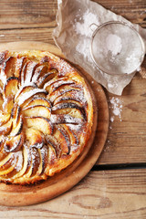 Homemade apple pie on cutting board on wooden background