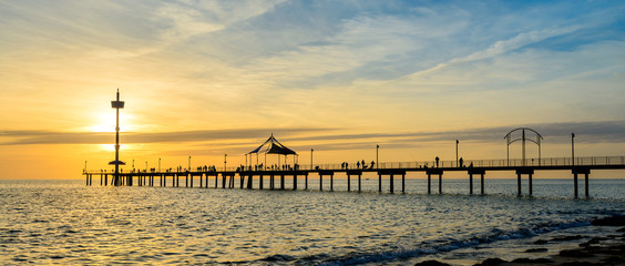 People fishing and walking on the Brighton jetty at sunset