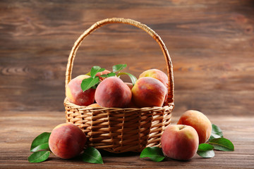 Fresh peaches in wicker basket on wooden background