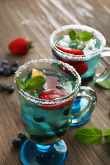 Glasses of berries juice on wooden table, closeup