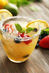 Glasses of berries juice with lemon on wooden table, closeup