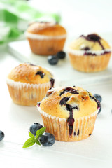 Tasty blueberry muffins on a white wooden background