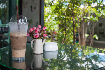 Iced coffee in a plastic cup is placed on a glass table.