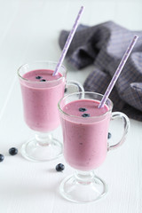 Fresh blueberry smoothie in the glasses on white wooden backgrou