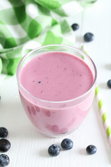 Fresh blueberry smoothie in the glass on white wooden background