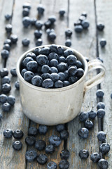 Blueberries in mug on a blue wooden background