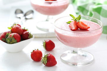 Tasty strawberry mousse in glass on white wooden table
