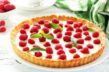 Sweet tart cake with raspberries on white wooden background
