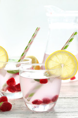 Raspberries and juice in glass on white wooden background