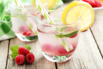 Raspberries and juice in glass on grey wooden background