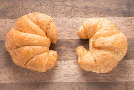 Two tasty croissants on wooden background, top view