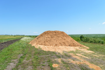 Big pile of yellow sand in the middle of the field
