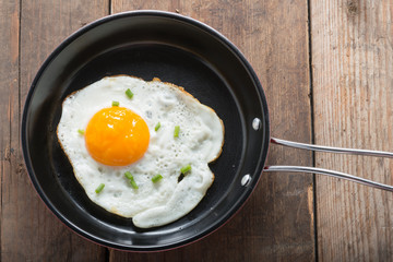 Fried eggs in pan with handle on table, top view