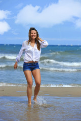 Fototapeta na wymiar young beautiful girl walking on water at sea shore smiling happy