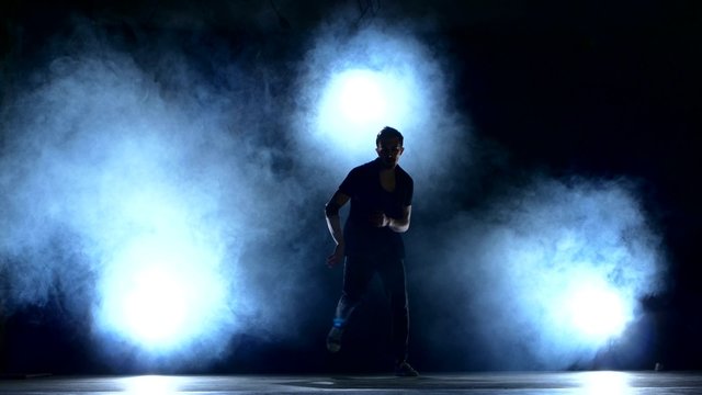 One hip hop break-dancer stylish man dancing, smoke, silhouette