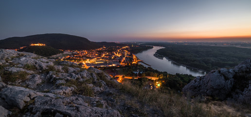 View of Lit Small City with River from the Hill at Sunset