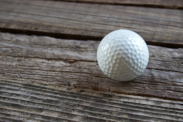 Old used golf ball on wooden background