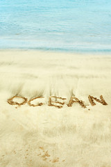Word handwritten in wet sand on Atlantic ocean shore