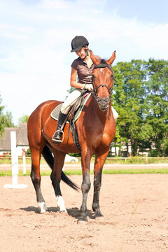 Teenage girl equestrian riding thoroughbred horseback. Vibrant summertime outdoors image.