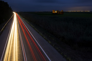 Car lights trails at night on the road towards the city