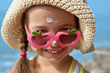 Happy child in glasses with sunscreen on the face