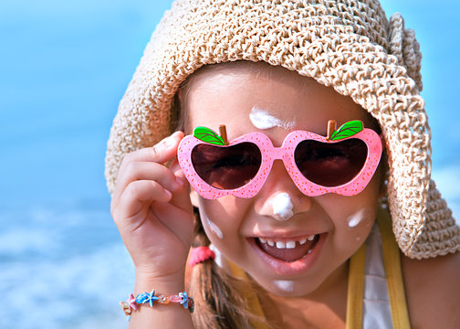 Happy child in glasses with sunscreen on the face