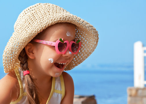 Happy child in glasses with sunscreen on the face