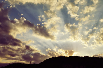 Beautiful sky with sunbeams and dynamic clouds at sunset.