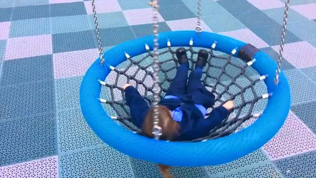 Slow motion of a happy little girl swings on Birds Nest Swing at the playground