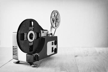 Naklejka premium abstract black and white image of old 8mm Film Projector over wooden table