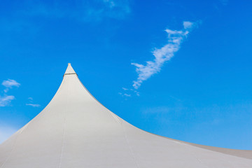 Top of white canvas tent against clear blue sky background.