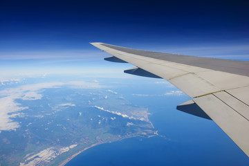 Obraz na płótnie Canvas Airplane flying over ocean and island