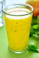 Cooling Mango mint smoothie, summer drink on green table, Yellow Tropical Smoothie made with mango, mint and lime juice.