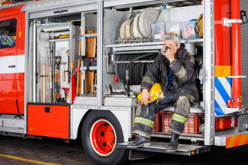 Naklejka premium Fireman Drinking Coffee While Sitting In Truck