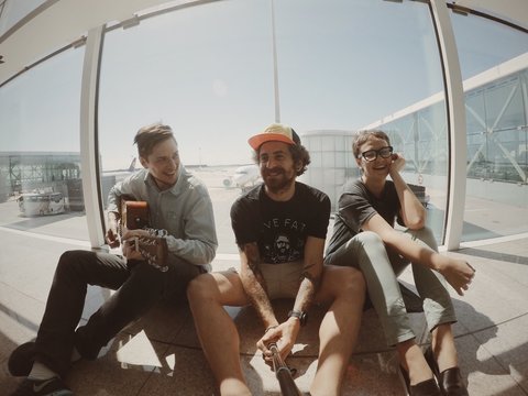 three friends are happy singing in airport before their flight