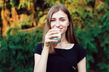 A beautiful , young girl drinking milk in the park .
