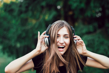 Beautiful , happy girl listening to music on headphones .