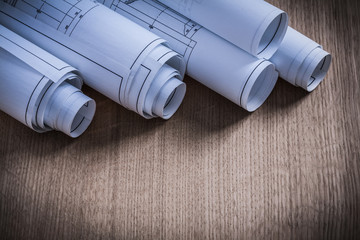 Stack of rolled construction plans on wooden background © mihalec