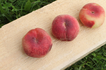 The ripe peaches lying on a wooden basis in a garden