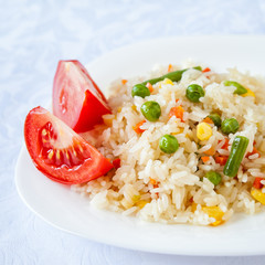 Rice with fried vegetables served with fresh tomato